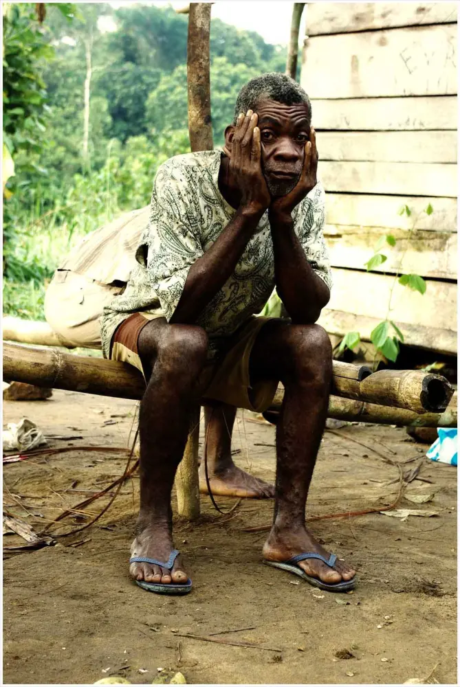 Homme assis devant une case
